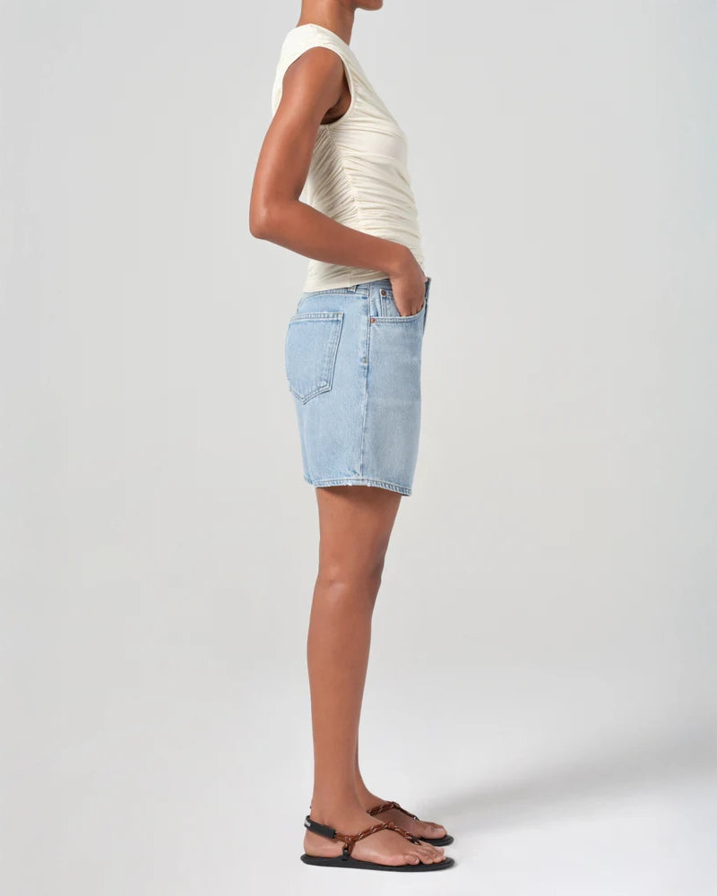 Person wearing mid rise light blue denim shorts 