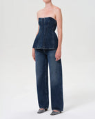 Woman wearing a denim strapless corset top by Agolde