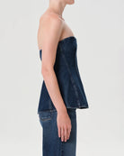 Woman wearing a denim strapless corset top by Agolde