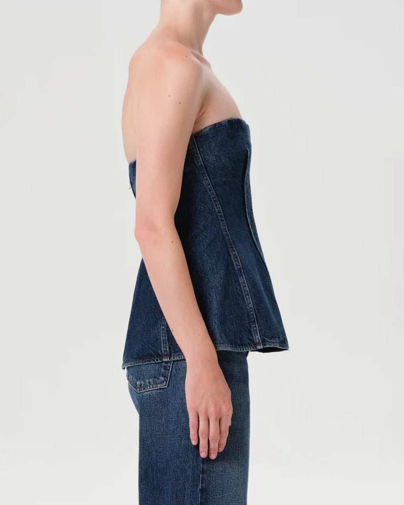 Woman wearing a denim strapless corset top by Agolde