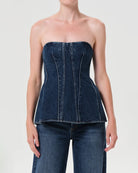 Woman wearing a denim strapless corset top by Agolde