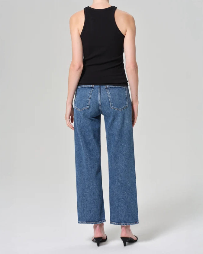Person wearing mid rise blue jeans in medium wash