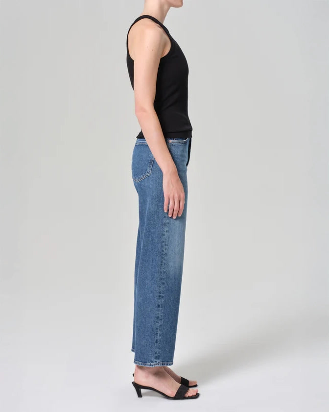Person wearing mid rise blue jeans in medium wash