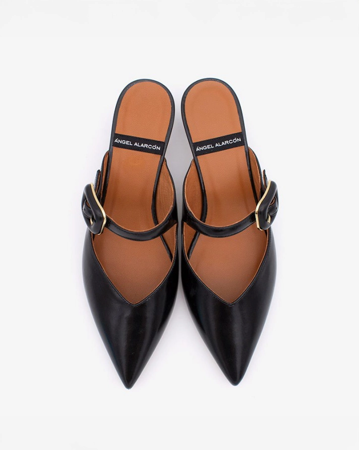 pointed toe mule with an open back and a small heel. Has a strap across the foot that has a black buckle on it