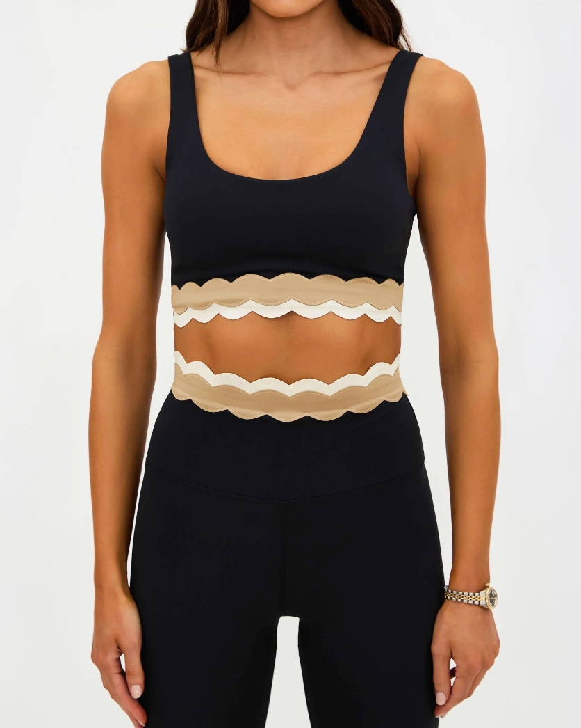 Woman wearing a black sports bra with beige ruffle detail