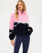 a woman wears a plush sherpa quarter zip sweater in pink with a navy blue mountain top