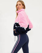 a woman wears a plush sherpa quarter zip sweater in pink with a navy blue mountain top