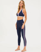 a woman wears a pair of navy leggings with pink and white stripes by Beach Riot