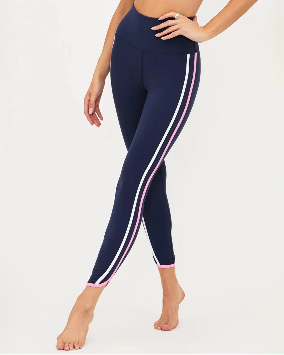 a woman wears a pair of navy leggings with pink and white stripes by Beach Riot