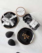 makeup flat lay of love tray, beauty blenders and a glass jar of black satin scrunchies for gifting
