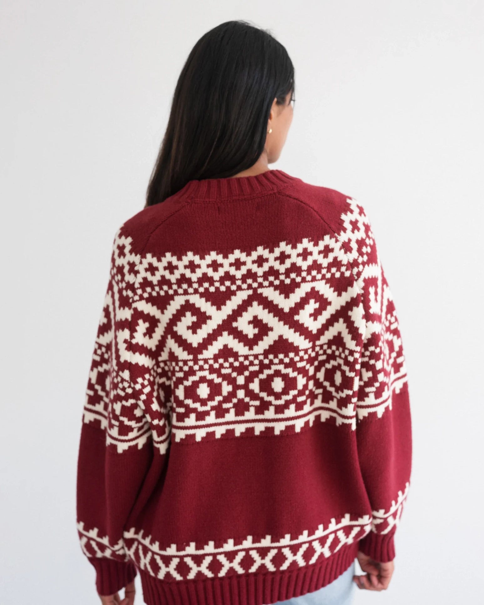 a woman wearing a fairisle sweater in burgundy with white accents