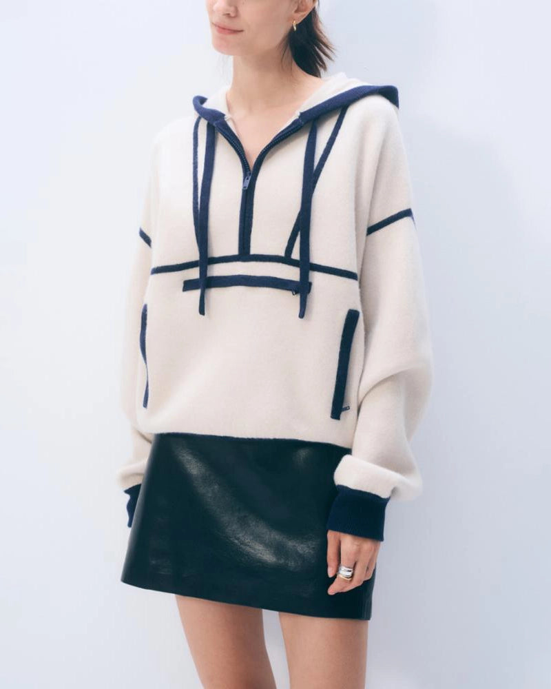 A woman wearing an ivory cashmere hoodie with navy accents