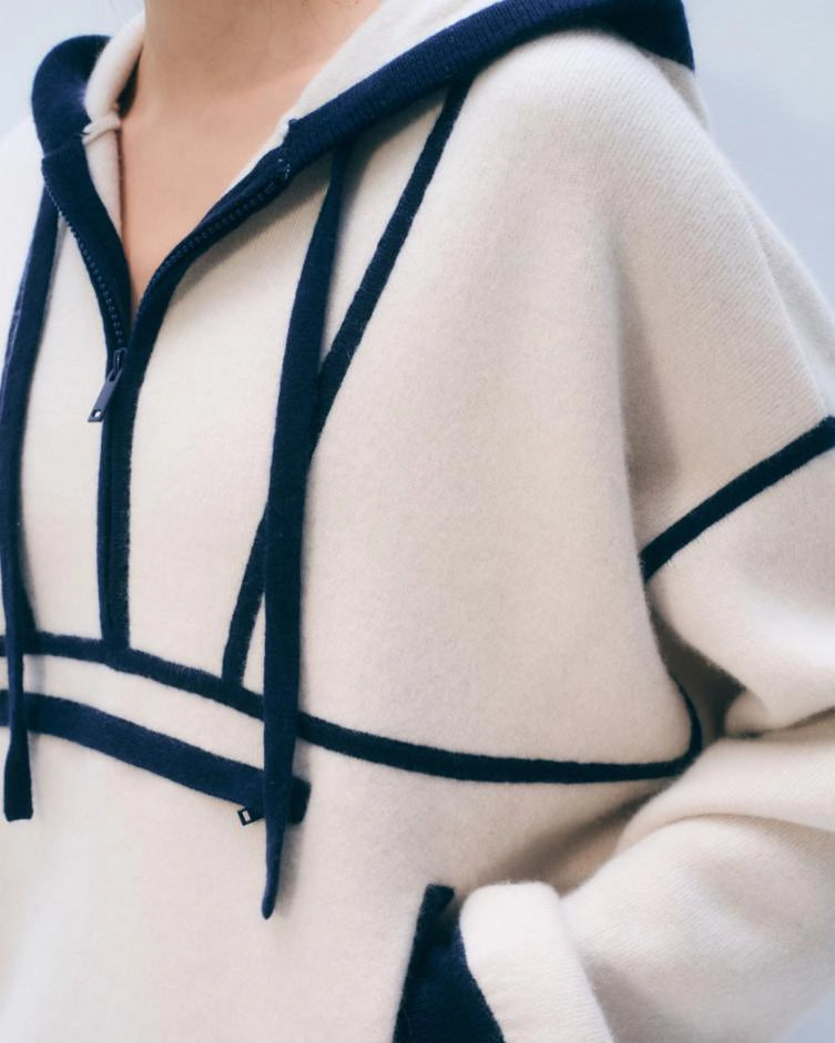 A woman wearing an ivory cashmere hoodie with navy accents