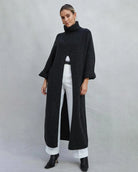 Woman wearing a long turtleneck sweater dress in black with a large slit up the front