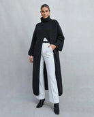 Woman wearing a long turtleneck sweater dress in black with a large slit up the front