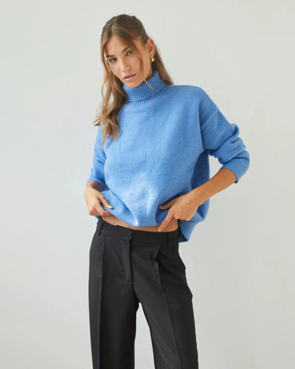 Woman wearing a relaxed fit high neck sweater in cornflower blue