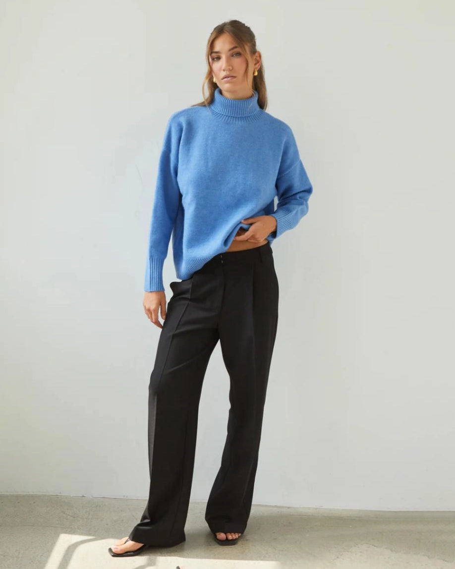 Woman wearing a relaxed fit high neck sweater in cornflower blue