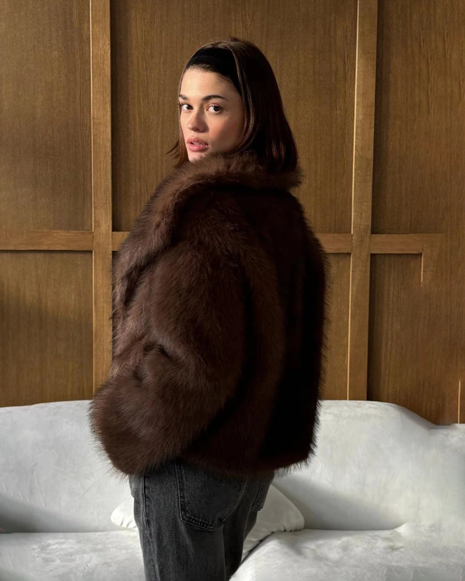 a woman wears a faux fur coat in brown with big lapels