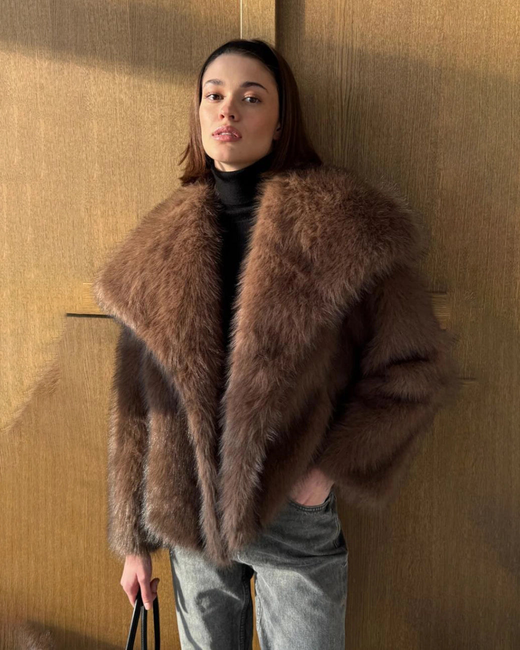 a woman wears a faux fur coat in brown with big lapels