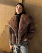 a woman wears a faux fur coat in brown with big lapels