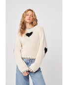 cream sweater with black heatrs all over