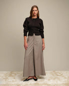 Woman wearing a black ribbed button down cardigan and beige wide-leg pants