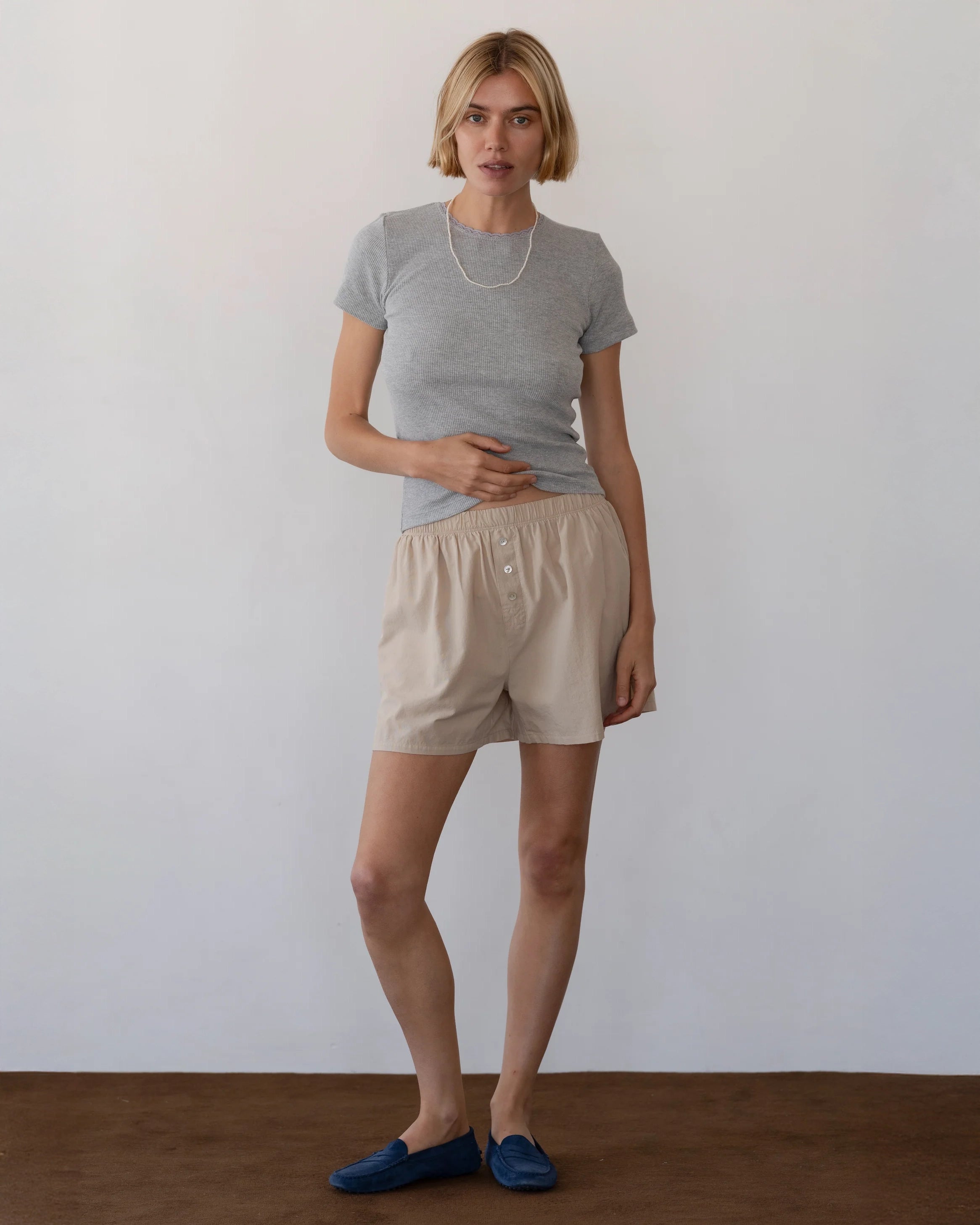 Person wearing beige cotton boxer shorts with grey t-shirt