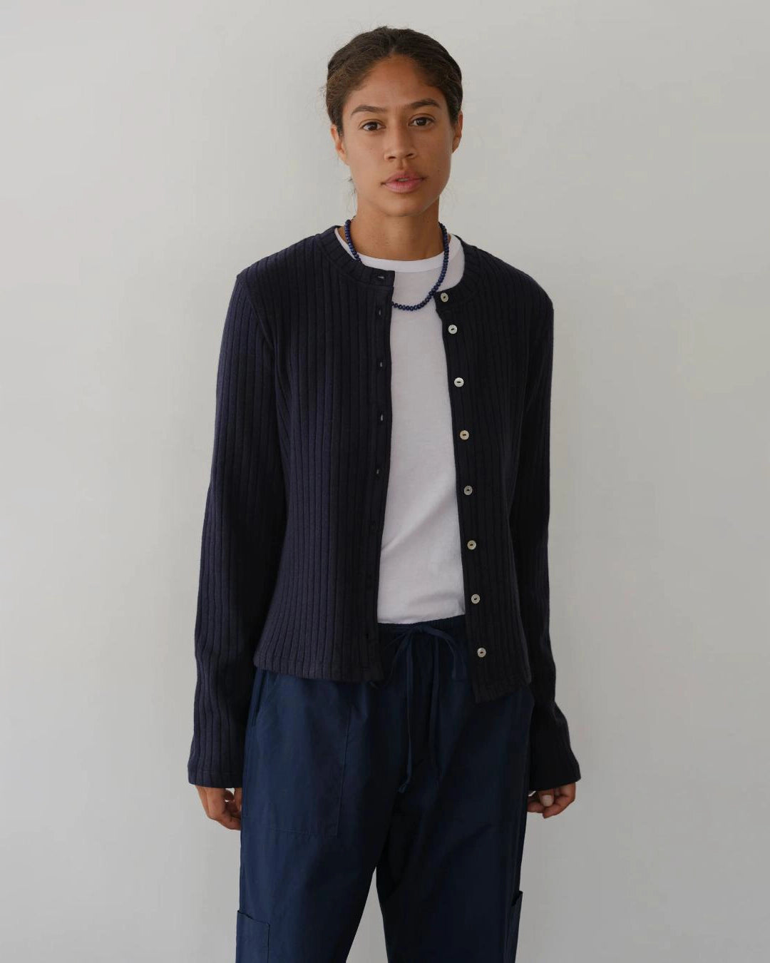 a woman wearing a dark navy blue ribbed button down cardigan 