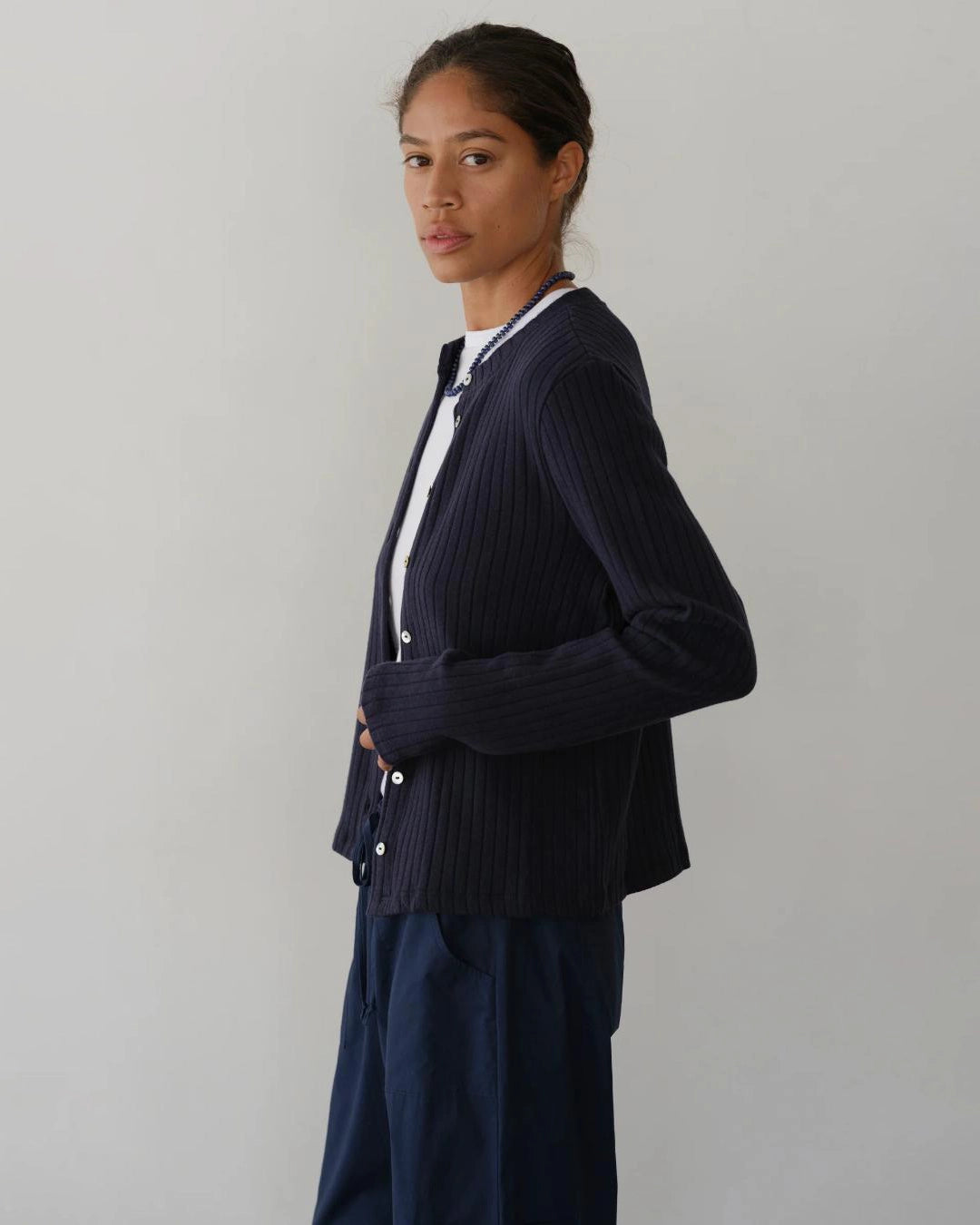 a woman wearing a dark navy blue ribbed button down cardigan 