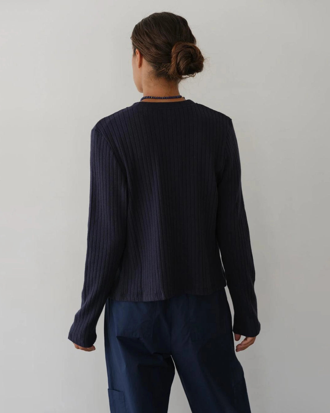 a woman wearing a dark navy blue ribbed button down cardigan 