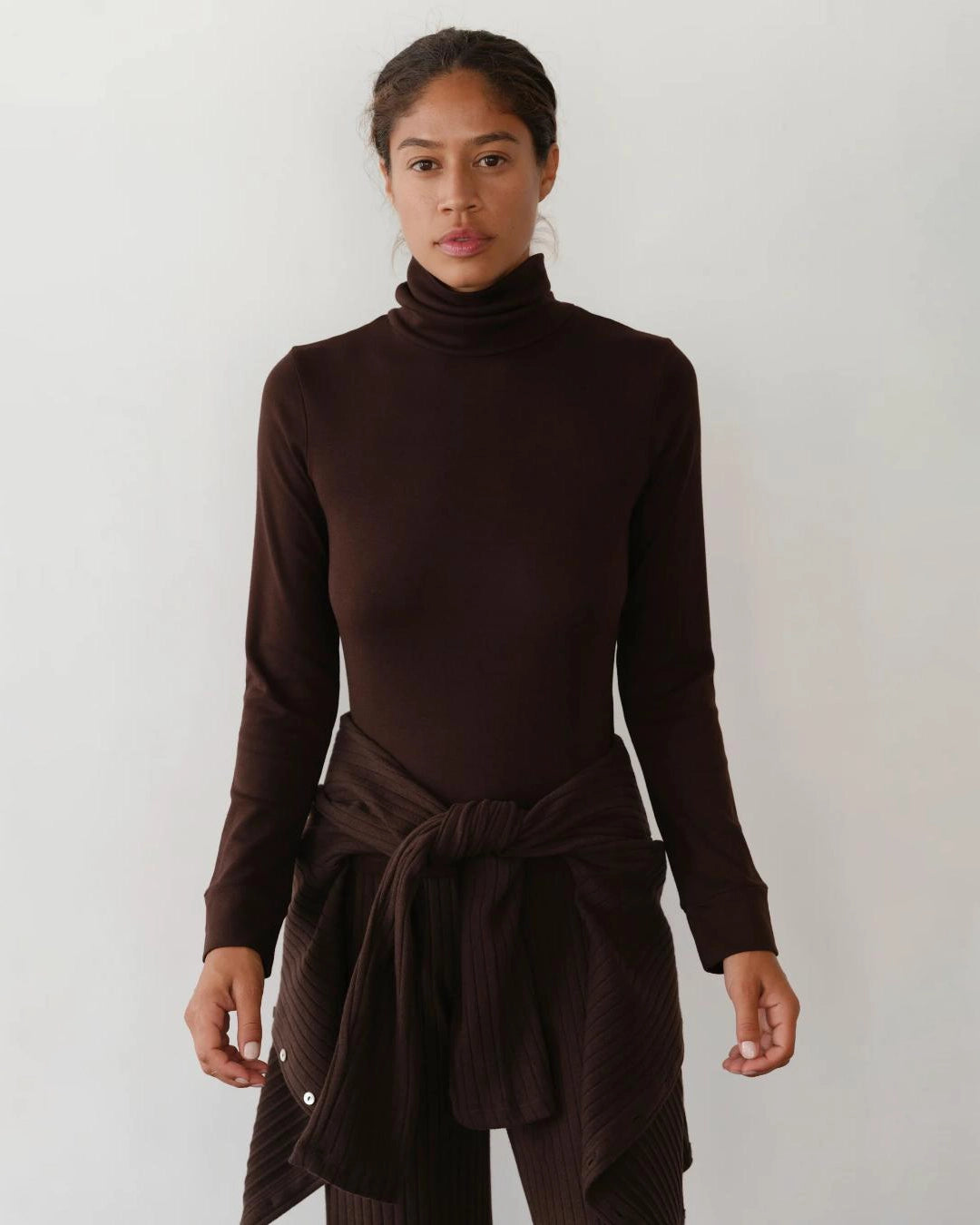 Woman wearing a brown turtleneck rib top 