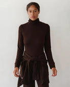 Woman wearing a brown turtleneck rib top 