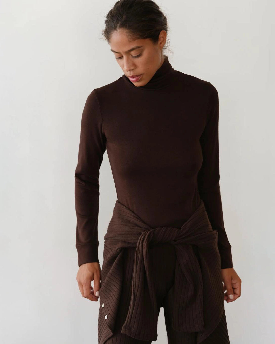 Woman wearing a brown turtleneck rib top 