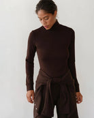 Woman wearing a brown turtleneck rib top 