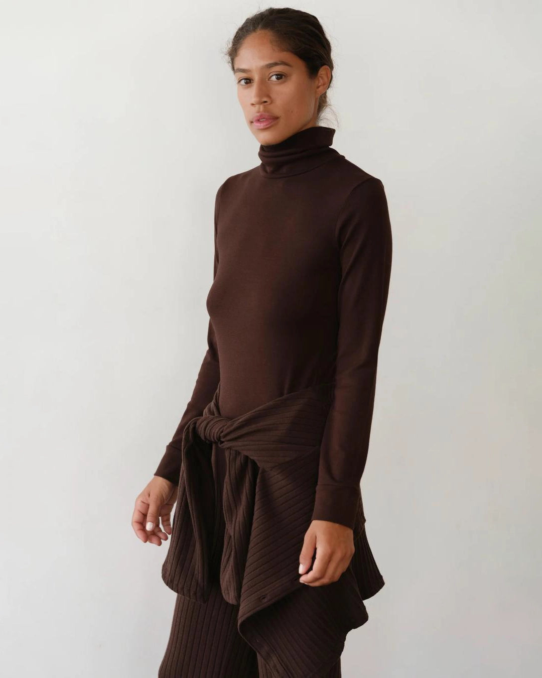 Woman wearing a brown turtleneck rib top 