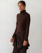 Woman wearing a brown turtleneck rib top 