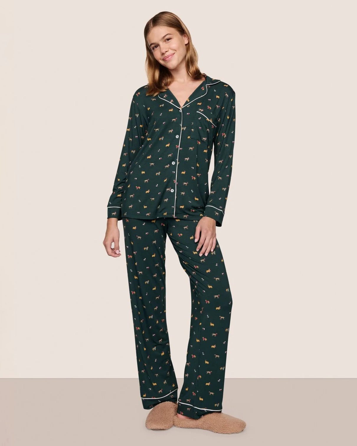 Woman wearing a dark green pajama set with a holiday dog pattern 