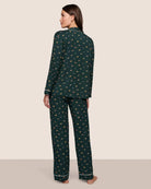 Woman wearing a dark green pajama set with a holiday dog pattern 