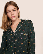 Woman wearing a dark green pajama set with a holiday dog pattern 