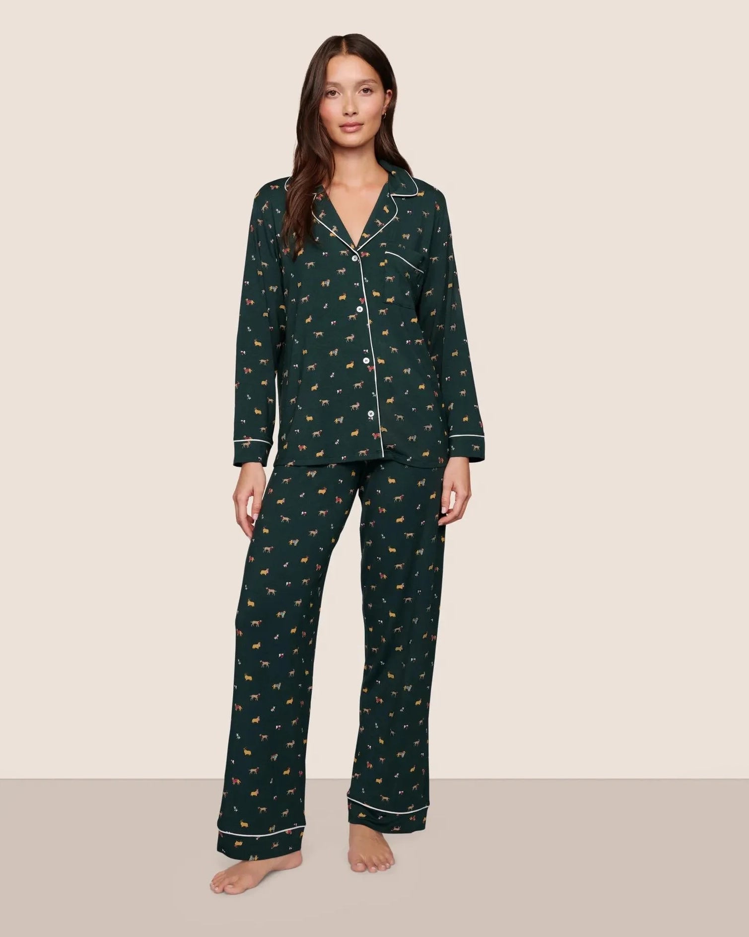 Woman wearing a dark green pajama set with a holiday dog pattern 