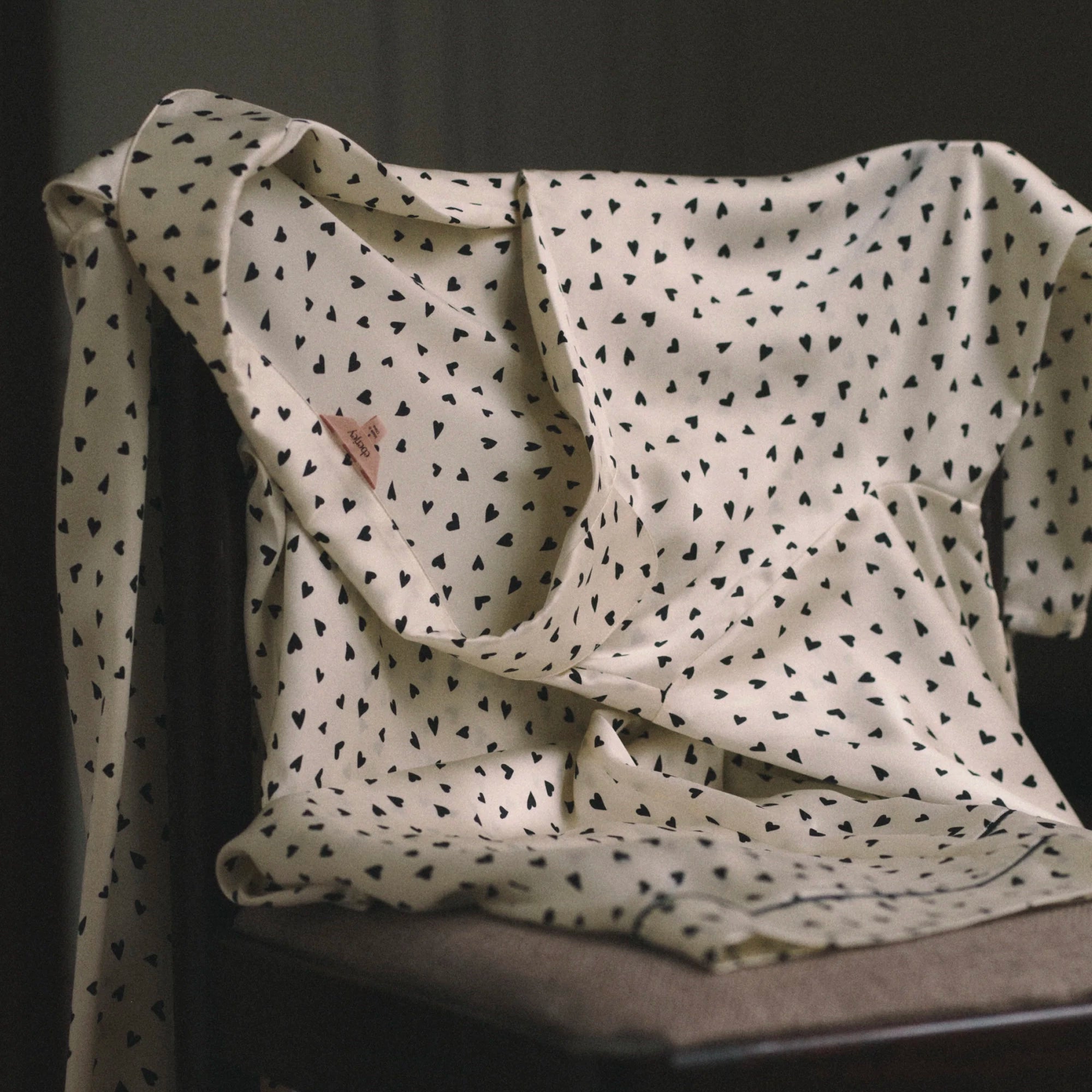 a pair of Eberjey pajamas over a chair in cream with black hearts on it