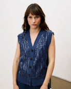 Woman wearing a blue sequin knit button down vest cardigan 