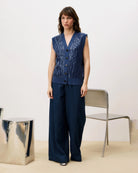 Woman wearing a blue sequin knit button down vest cardigan and wide blue pants