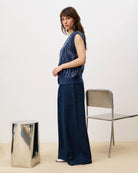 Woman wearing a blue sequin knit button down vest cardigan and wide blue pants