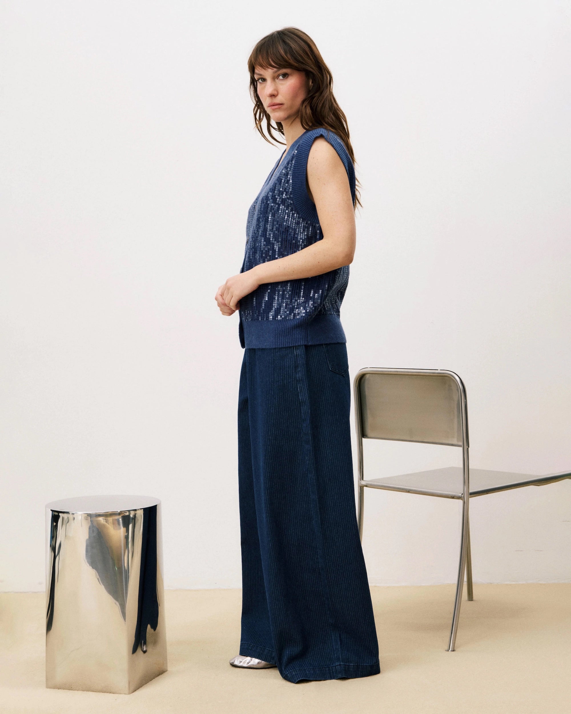 Woman wearing a blue sequin knit button down vest cardigan and wide blue pants