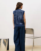 Woman wearing a blue sequin knit button down vest cardigan and wide blue pants