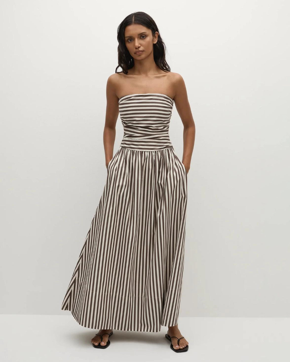 Woman wearing a strapless striped dress in beige and brown