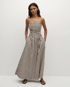 Woman wearing a strapless striped dress in beige and brown