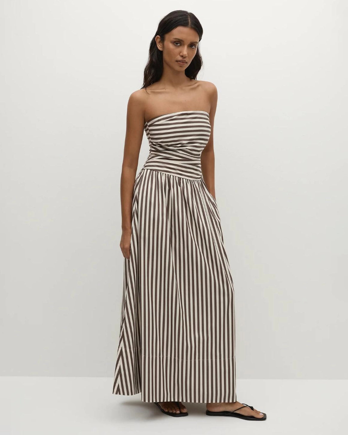 Woman wearing a strapless striped dress in beige and brown