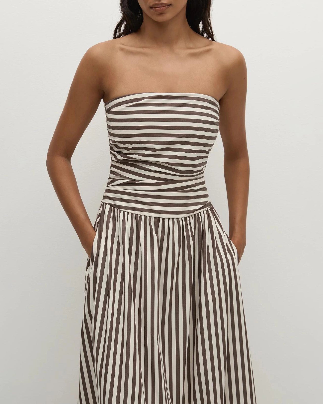 Woman wearing a strapless striped dress in beige and brown